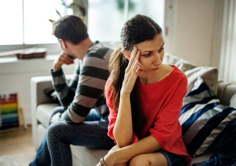 Upset couple sitting apart during a serious conversation about custody weekends, family routines, and their shared home.