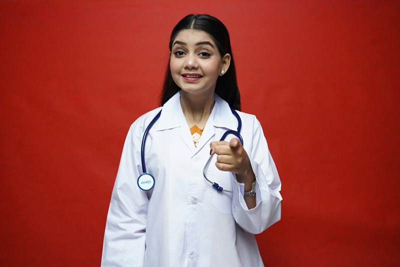 Young sister pretending to be a doctor with the doctor kit her sibling gave her as a birthday gift.