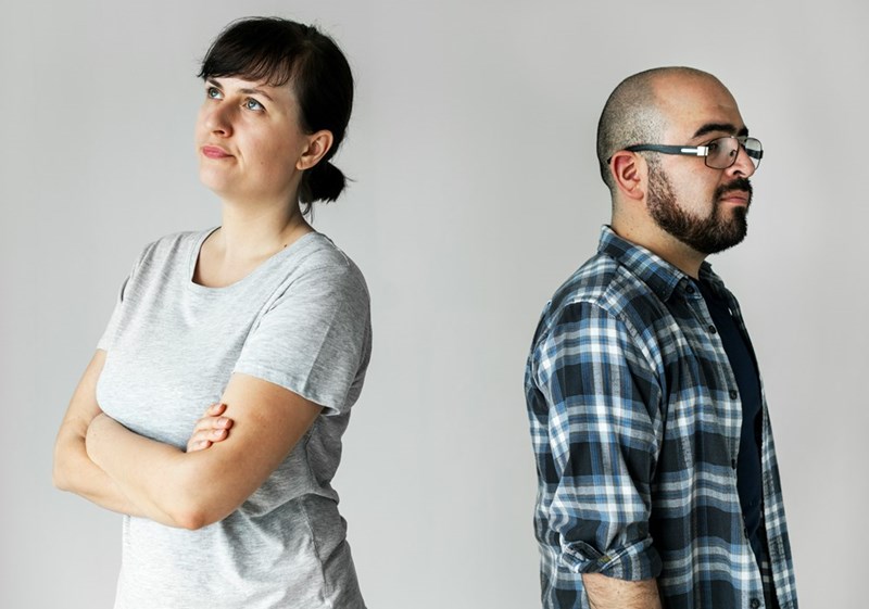Married couple standing back-to-back, reflecting the emotional distance caused by disagreements over inheritance and family expectations.