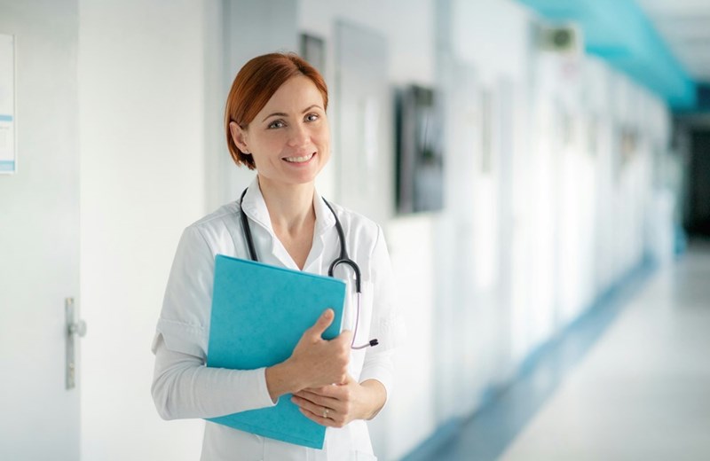 Potrait of woman doctor with clipboard standing in hospital copy space