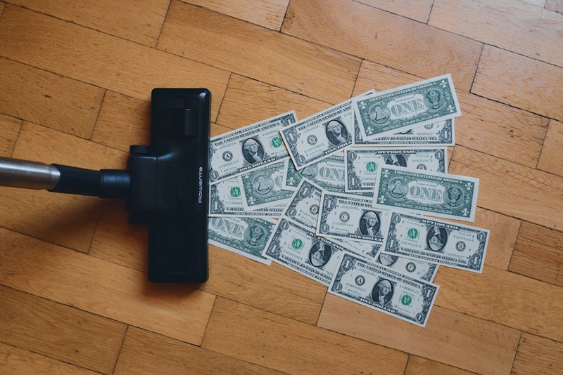 Money being cleaned from the floor by a vacuum cleaner.