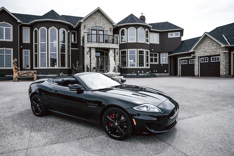 A mansion with an expensive car parked in front.