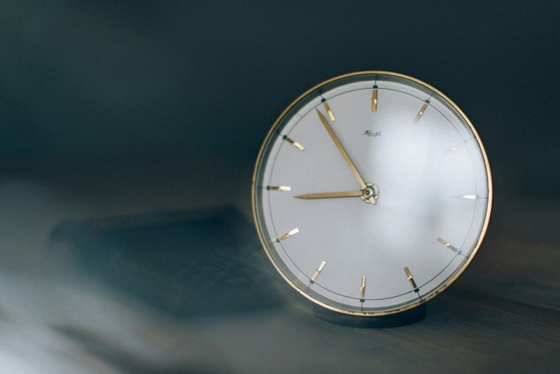 A white clock with gold arrows on a wall.