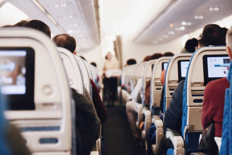A plane seen from the inside with passengers and cabin crew members. Representation.
