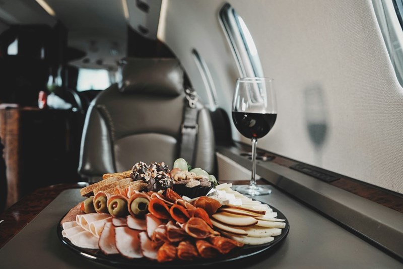 Plane food served with a wine glass and a plate full of cold cuts.