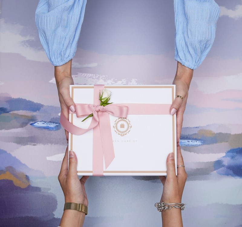 Two hands exchanging a beautifully wrapped gift box