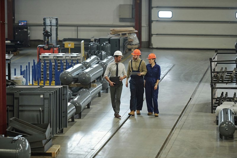 Factory workers walking among machines.