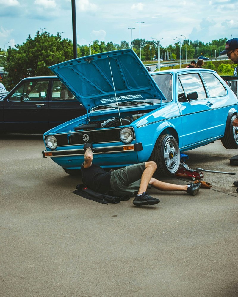 Person repairing a car outdoors during personal time on their day off.