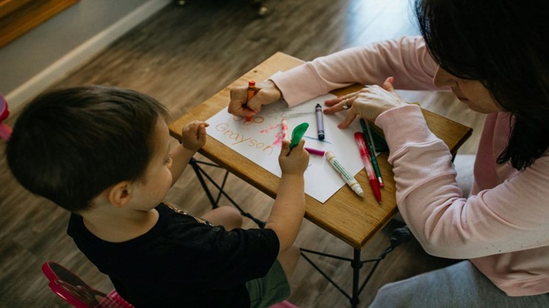 A child playing and coloring with a babysitter. Representation.