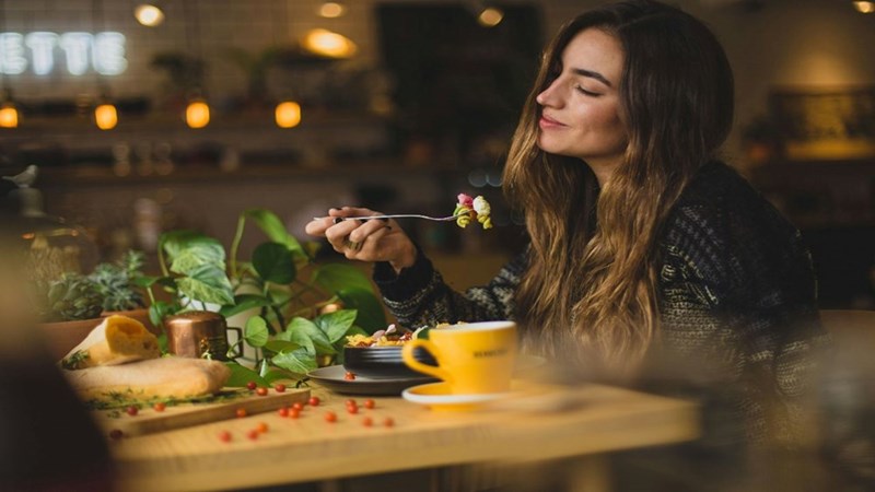 A woman eating food at a restaurant. Representation.