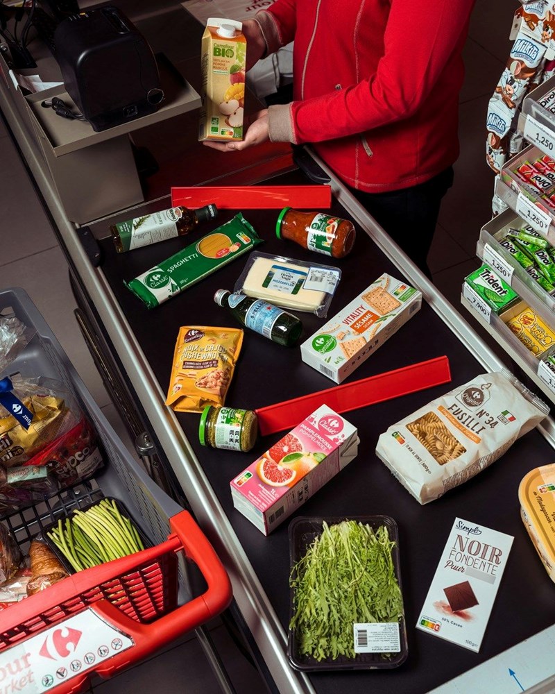 Cashier scanning groceries at a supermarket checkout counter after a costly shopping trip to help a friend.
