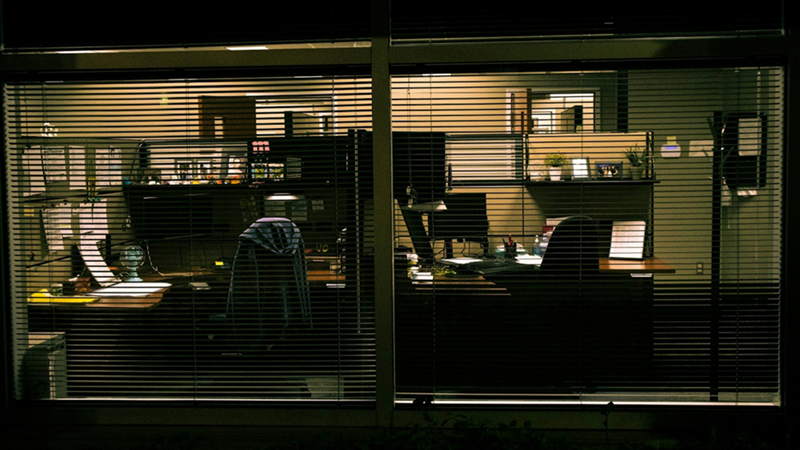 The view through an office window with the blinds down at night