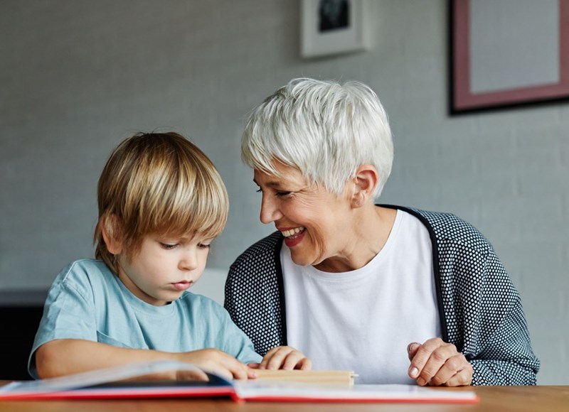 staged photo of an older woman warmly engaging with a young boy, like a family plan is being pushed despite his hesitation.