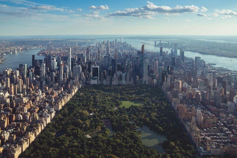 Aerial view of New York City skyline, highlighting the urban setting where an office worker questions a new policy requiring bike travel during work hours.