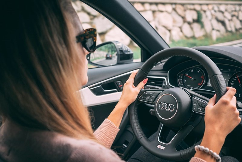 Woman driving a car while helping a family member with transportation.
