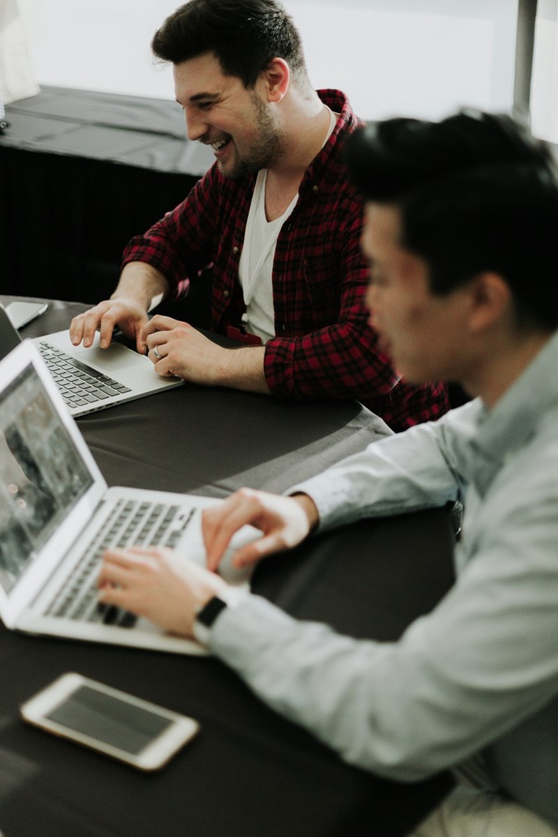 a couple of men sitting with laptop
