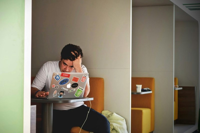 man using laptop and taking his hand to his head