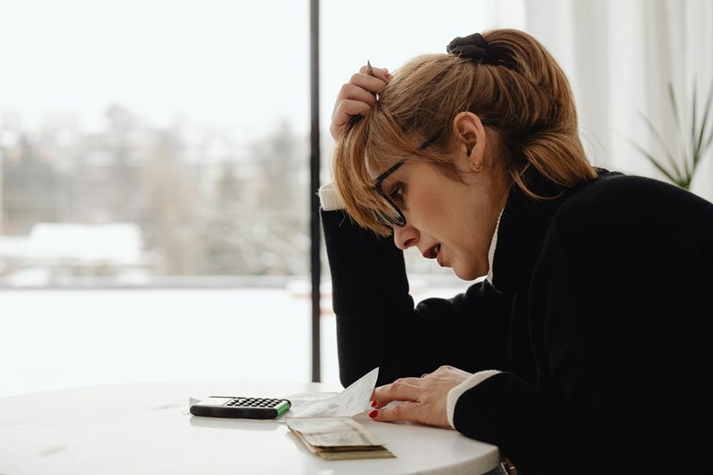 A woman looks at her phone on the table, distressed