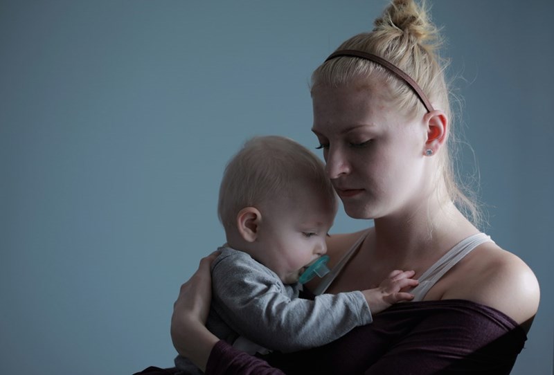A young mother cradles her baby in a quiet moment at home.