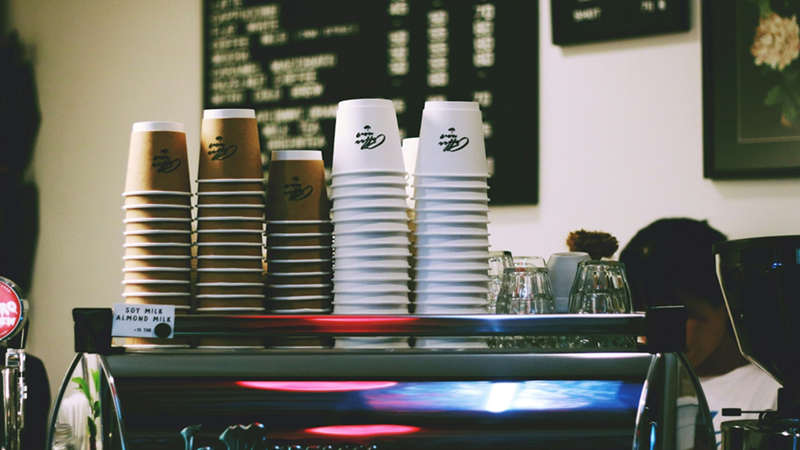 Disposable cups stacked on top of a coffee machine in a coffee shop