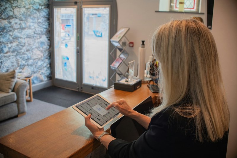 A woman at the front desk working on her tablet. Representation.