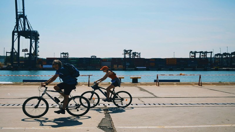 Two people riding bikes on the coast. Representation.