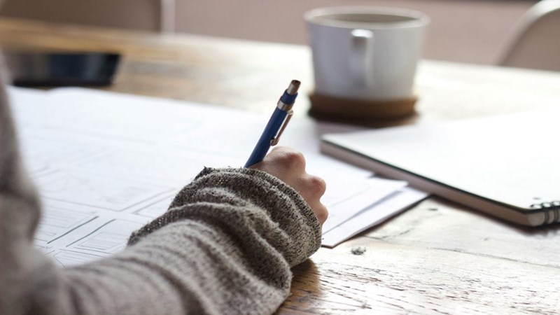 A student taking notes with pen and paper
