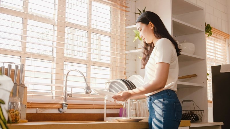 A 23-year-old woman is cleaning her dishes with ease. 