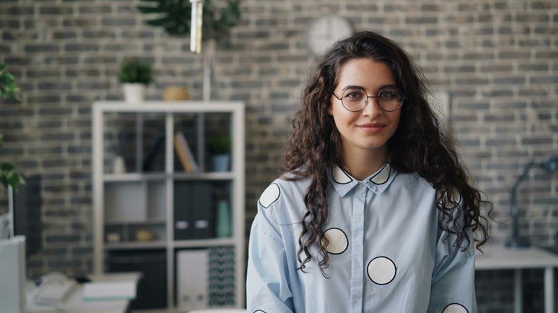 A female employee stands against a brick wall