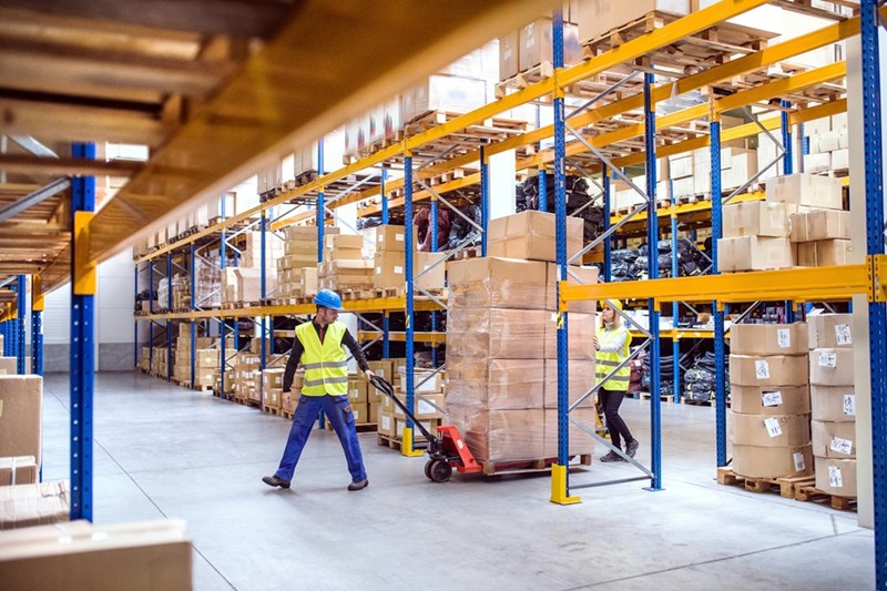 Employees working inside a busy distribution warehouse where inventory reports and shipping schedules are part of the daily operation.