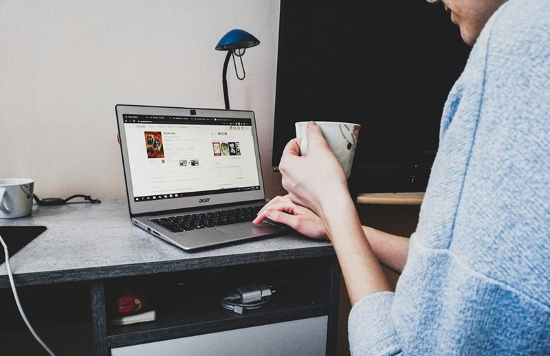 A person holds coffee while using their work computer