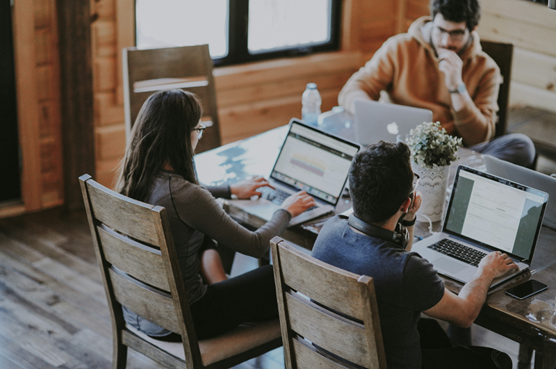 A pair of coworkers sit next to each other at a coworking table