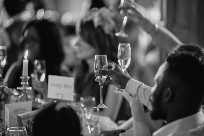 A grayscale photo of people giving a toast at a wedding