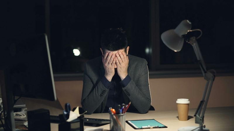 Man in suit at desk head in hands