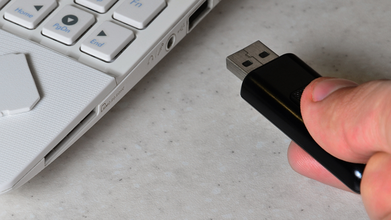 Hand Inserts a USB Stick into Laptop
