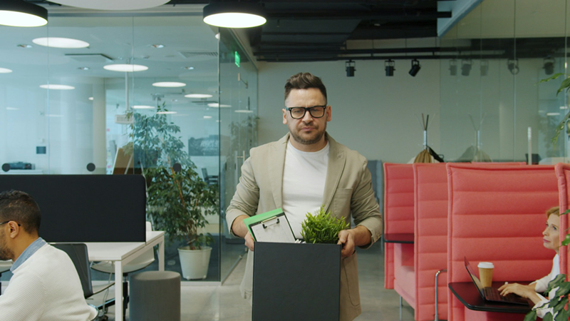 Another male employee carrying a box of belongings through an office