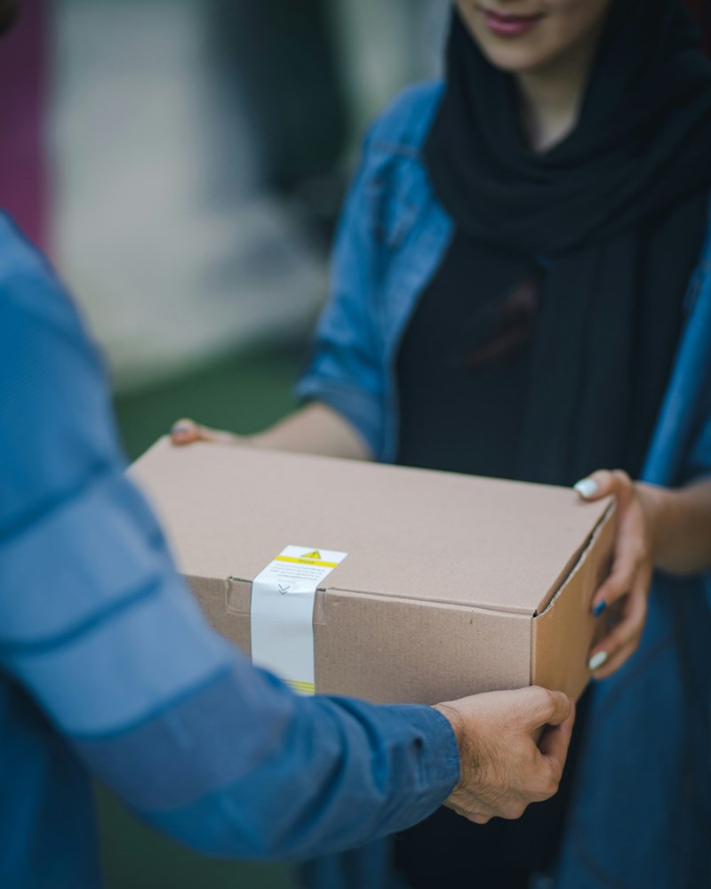 woman giving brown box to employee