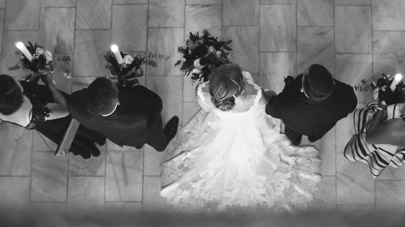 Grayscale photo of a top-down view of a bride surrounded by members of the bridal party.