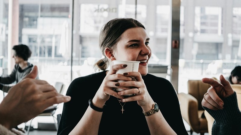 A coworker holds a cup of coffee in his hands