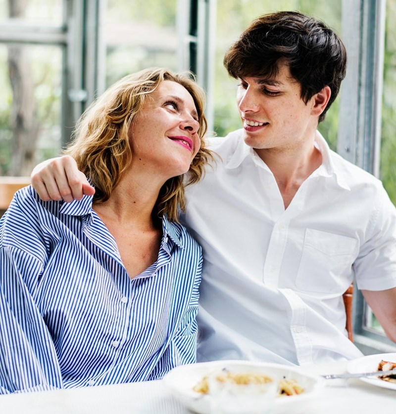 A couple sitting closely together at a restaurant and looking at each other with love.