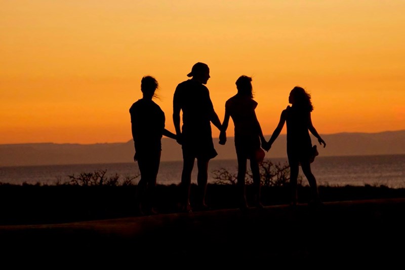 A family seen in the shadows near a shore. Image for illustrative purposes.