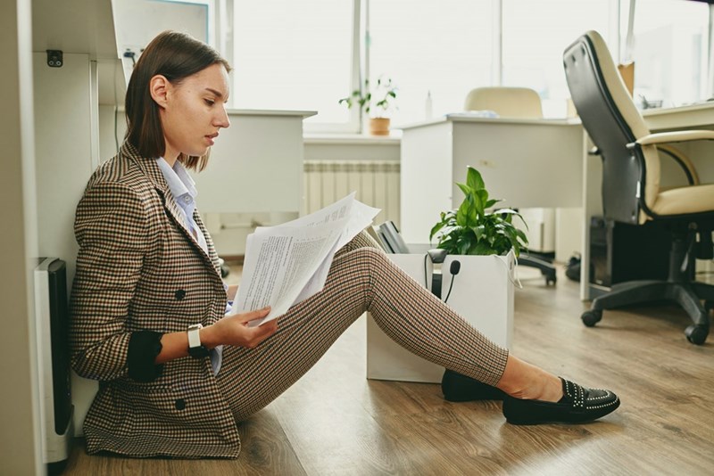 A businesswoman sits on the floor looking over documents in the office