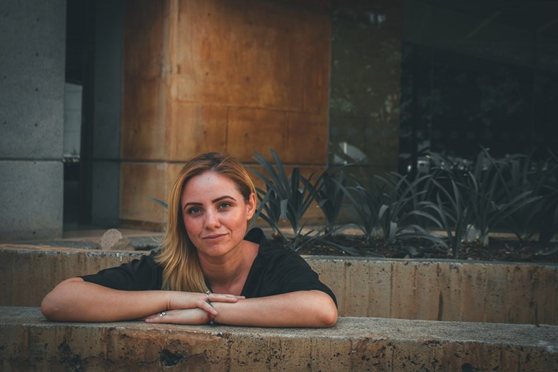 A woman with folded arms rests on a ledge