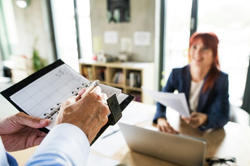 A businesswoman confronts her boss as he holds a folder of documents