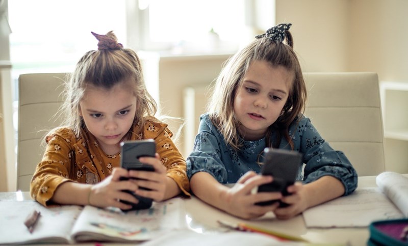 Homeschooled kids playing on their cell phones in the middle of their lesson.