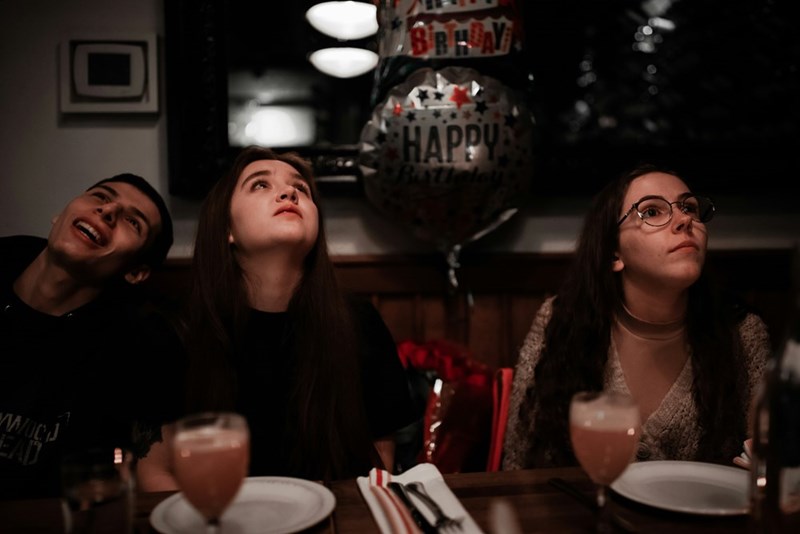 A group of people sit around a table on a woman's birthday dinner