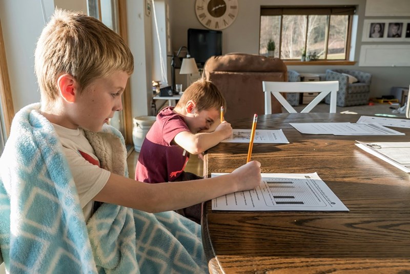 Two kids doing their homework at their kitchen table. Recreated scenario included to enhance reader understanding.
