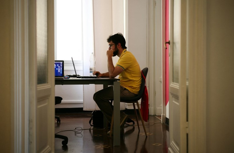 A stressed employee sits facing his laptop at a desk
