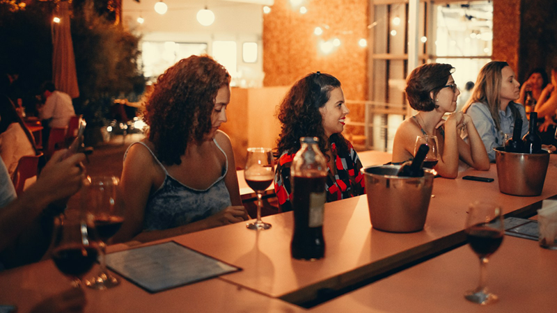 A group of colleagues sitting at a dining table with wine glasses at night.