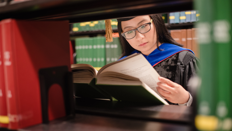 PhD student reading a book in the library.